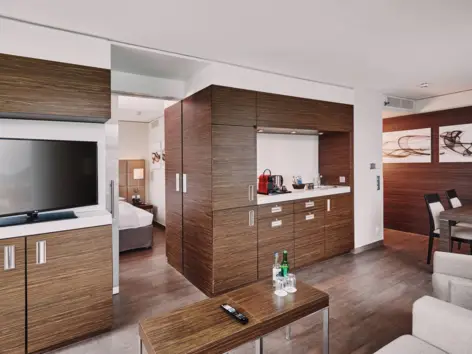 Wohnbereich der Suite vom H4 Hotel Solothurn mit einer kleinen Küche und einem TV Schrank.