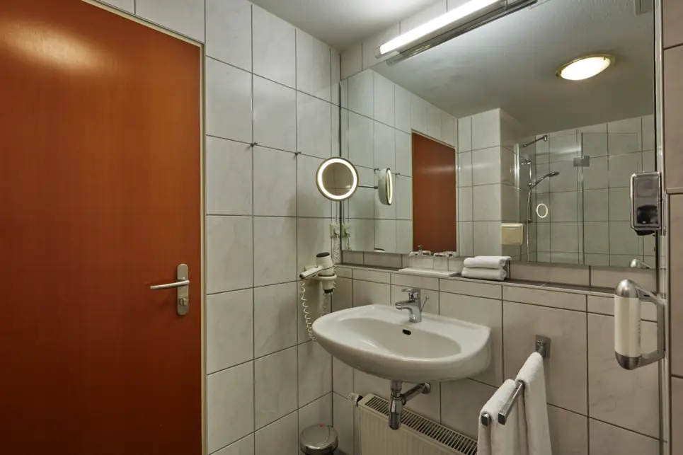 Cuarto de baño con un gran espejo sobre el lavabo.