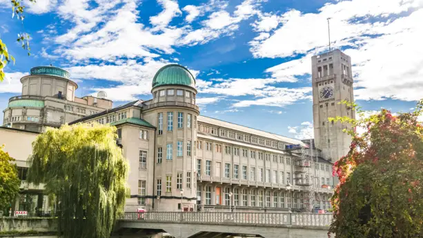 Deutsches Museum am Tag mit dem großen Glockenturm. Vor dem Museum steht eine große Weide.