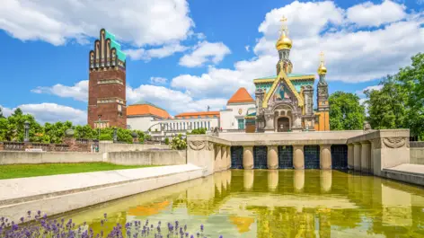 Hochzeitsturm auf der linken Seite und die russisch-orthodoxe Kirche auf der rechten Seite. Vor der Kirche steht ein kleines Wasserbecken.