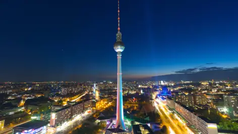 Überblick auf Berlin bei Nacht. In der Mitte steht der Fernsehturm beleuchtet.