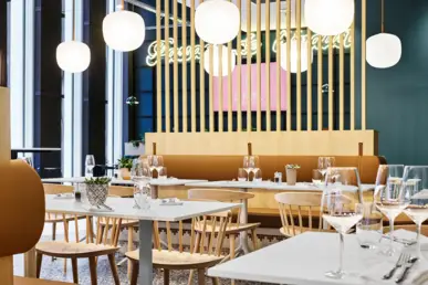 Seating in the restaurant with glasses and cutlery on the tables.