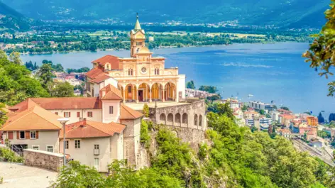 Madonna del Sasso auf einem Berg umgeben von Wald. Im Tal ist Locarno und der Lago Maggiore.