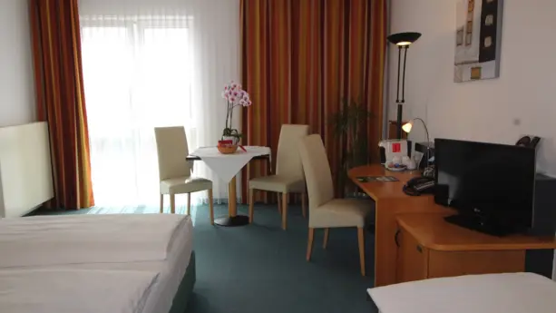 Hotelzimmer mit einem Schreibtisch und einer kleinen Sitzgruppe daneben.