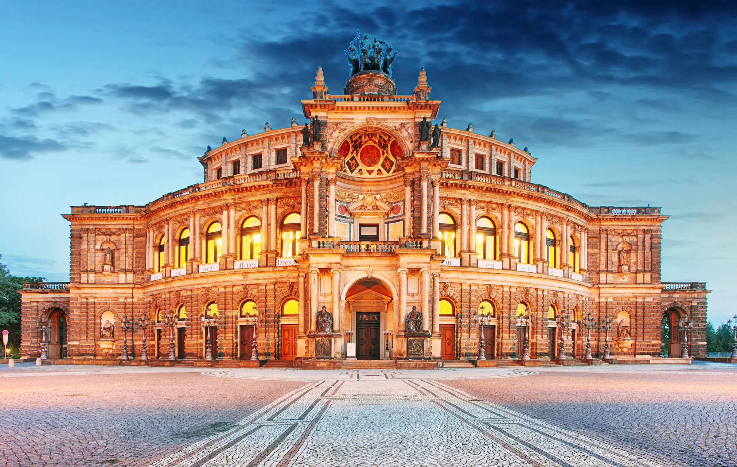 Beleuchtete Semperoper im Sonnenuntergang.