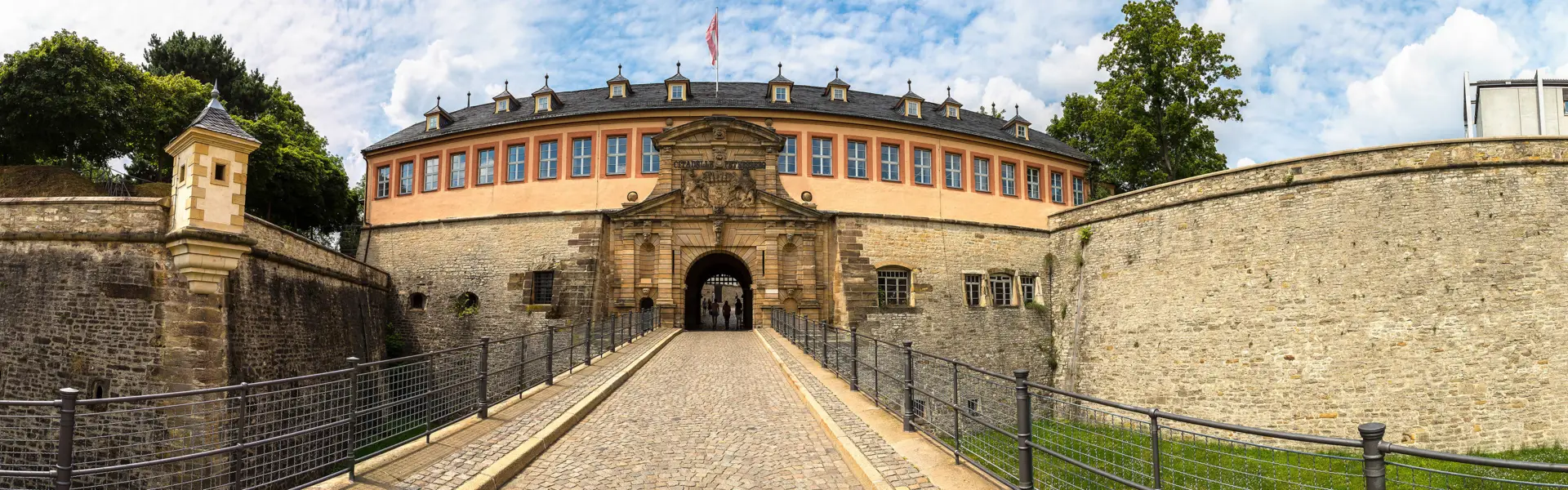 Eingang über eine Brücke von der Zitadelle Petersberg. Links und rechts stehen hohe Mauern.