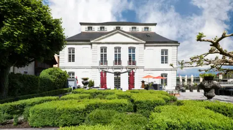 Palais Besenval mit einem großen Garten. Im Garten sind viele in Form geschnittene Hecken,