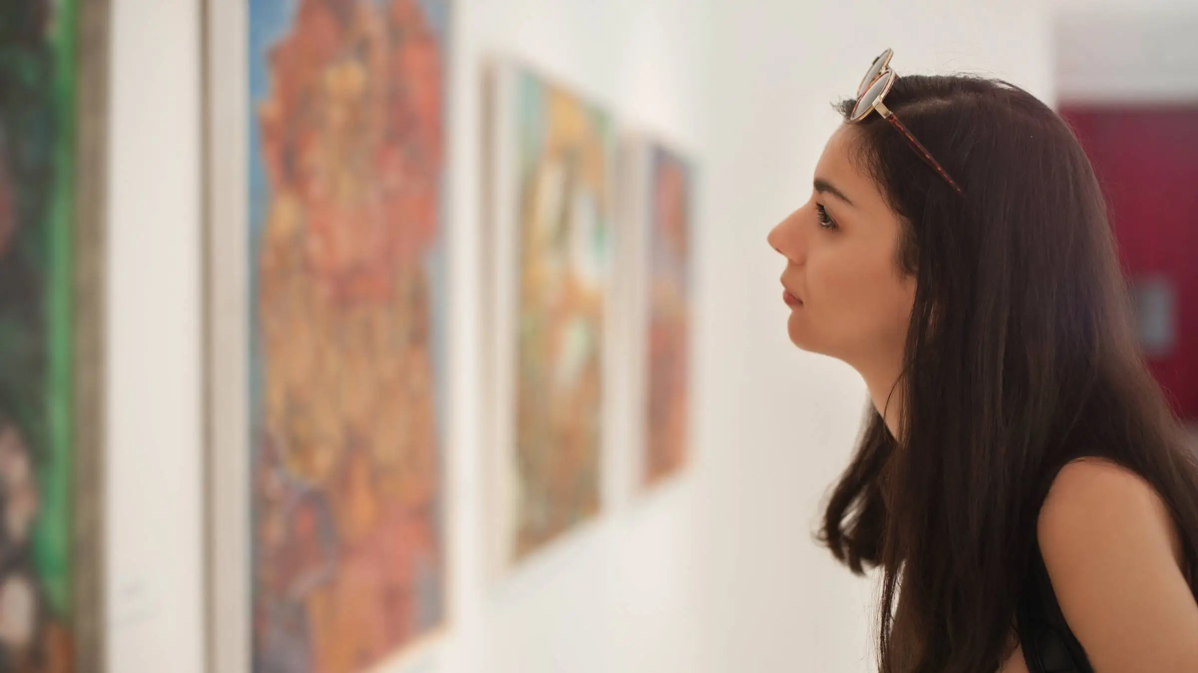 Woman with dark hair looks closely at a painting