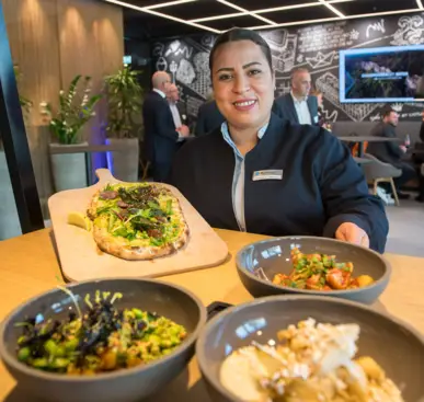 Eine Mitarbeiterin des Hotels präsentiert Street Food in kleinen Schüsseln und auf einem Holzbrett.