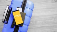 Ein Smartphone, das auf einem blauen Koffer liegt. Auf dem Bildschirm ist der Text "Smart Check-in & out" auf einem gelben Hintergrund.