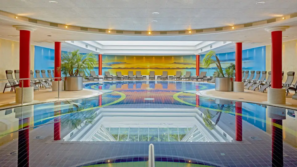 Piscine avec un grand bassin et des chaises longues au bord.