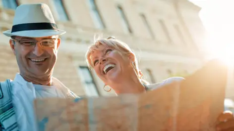 Ein Mann und eine Frau halten einen Stadtplan in der Hand und lächeln sich an.