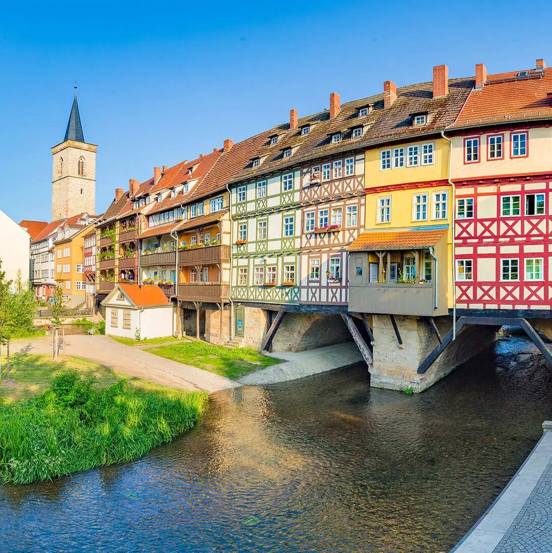 Blick auf die Krämerbrücke mit bunten Fachwerkhäusern. Links im Hintergrund die Ägidienkirche.