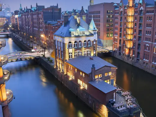 Kanäle von der Speicherstadt bei Nacht. Die Gebäude sind indirekt beleuchtet.