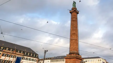 Steinsäule mit einer Statue auf der Spitze von unten.