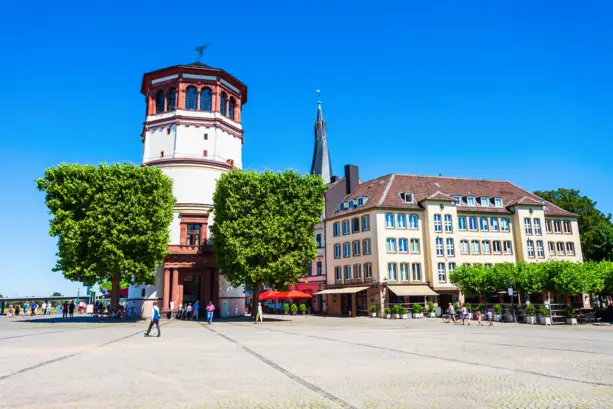 Schlossturm mit einem Vorplatz. Daneben ist ein Café.