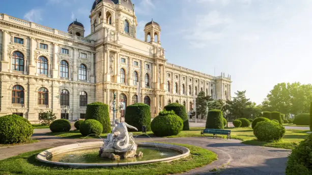 Kunsthistorisches Museum mit einem Park davor. Im Park stehen verschiedene in Form geschnittene Hecken und ein kleiner Brunnen.