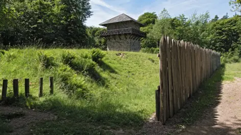 Kleiner Wehrturm und eine Holzpalisade.