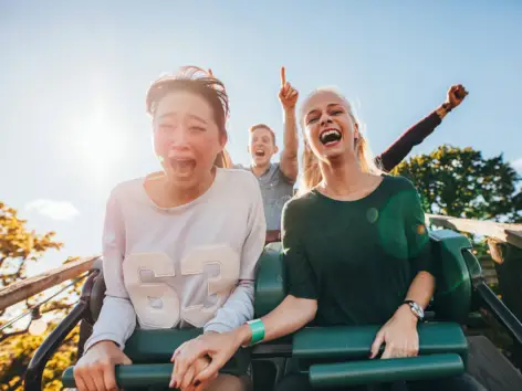 Zwei Frauen sitzen in einer Achterbahn und schreien.