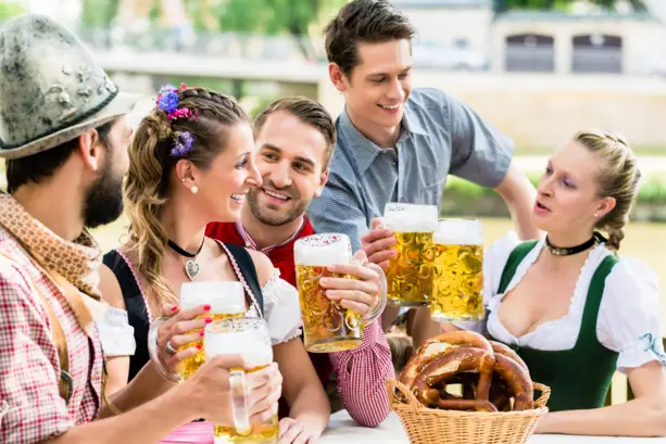 Eine Gruppe von Menschen im Trachtenoutfit prosten sich mit Bier zu.