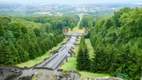 Bergpark Wilhelmshöhe avec une grande forêt. Entre la forêt, il y a un grand escalier.