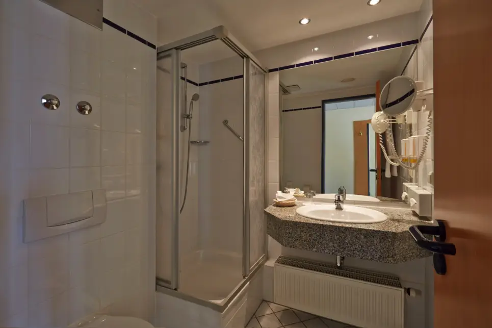 Salle de bains avec une douche et un lavabo à côté.