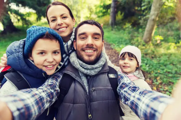 Eine Familie steht im Wald und schießt ein Selfie.