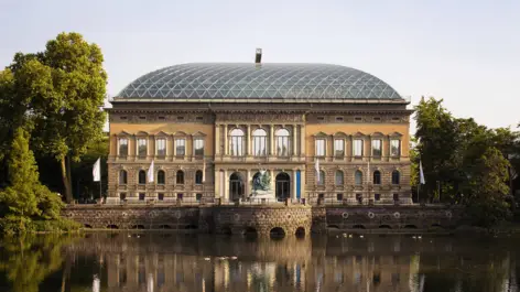 Kunstsammlung NRW mit einem großen Glasdach. Vor dem Gebäude ist ein großer Teich.