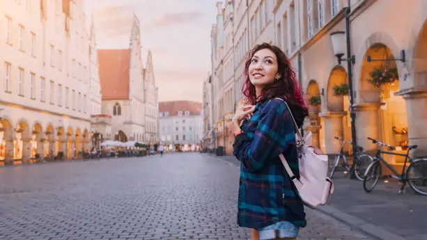 Eine Frau steht seitlich auf dem Prinzipalmarkt und blickt lächelnd in die Kamera.