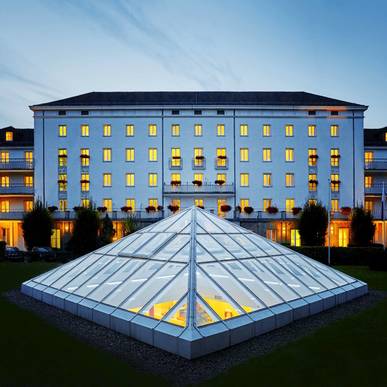 Blick durch die gläserne Pyramide vom Hotel in den Wellnessbereich unter der Erde bei Nacht.