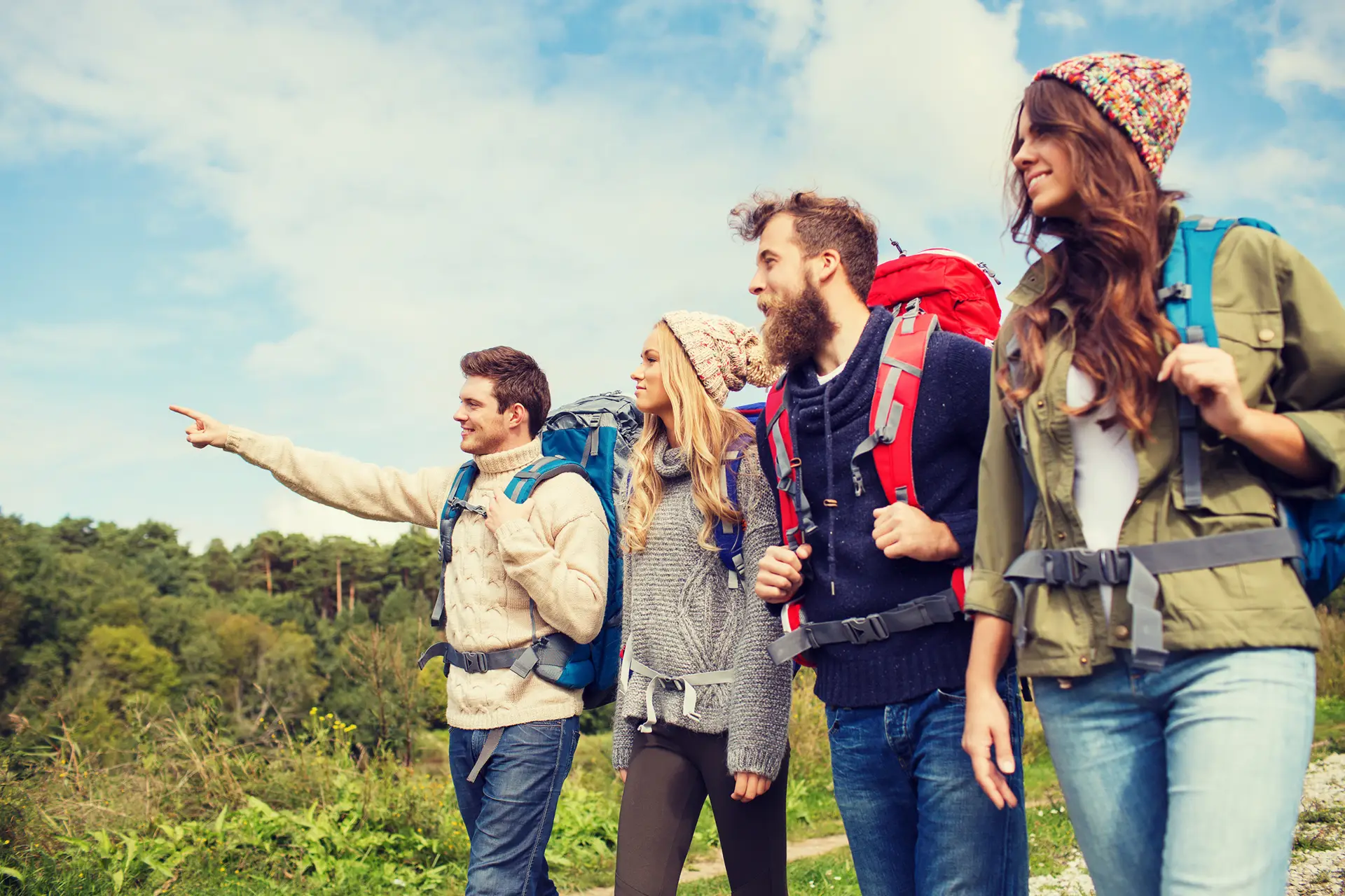 Zwei Männer und zwei Frauen wandern auf einem Weg. Ein Mann zeigt auf etwas.