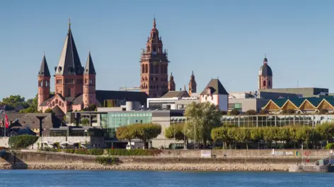 Blick über den Rhein mit dem weißen Eisenturm im Vordergrund. Im Hintergrund steht der Mainzer Dom.