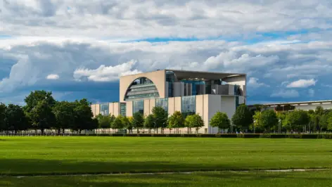 Bundeskanzleramt mit einer Allee und einer großen Wiese davor.