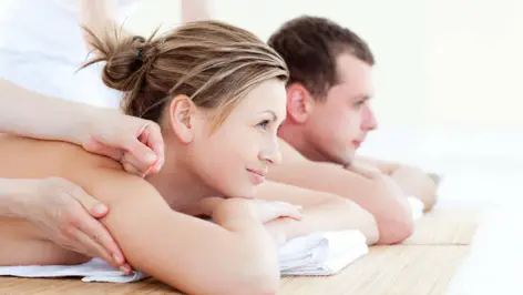 Une femme et un homme sont allongés sur une table de massage.