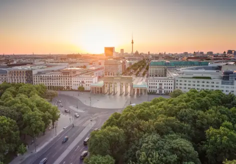 Blick über Berlin  vom Tiergarten aus während des Sonnenuntergangs. In der Mitte des Bildes steht das Brandenburger Tor.