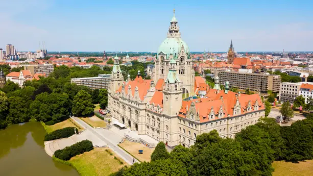 Neues Rathaus mit seinem Turm in der Mitte, welcher ein grünes Dach hat. Im Hintergrund ist Hannover zusehen.