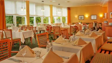 Des tables dressées avec une nappe blanche devant de grandes fenêtres dans le restaurant.