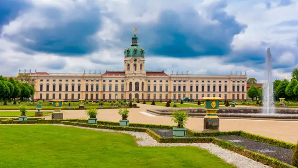 Schlossgarten vom Schloss Charlottenburg mit dem schloss im Hintergrund. Auf der rechten Seite steht ein Springbrunnen.