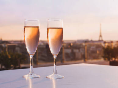 Deux coupes de champagne au coucher du soleil. En arrière-plan, le bruit de la tour Eiffel est flou.