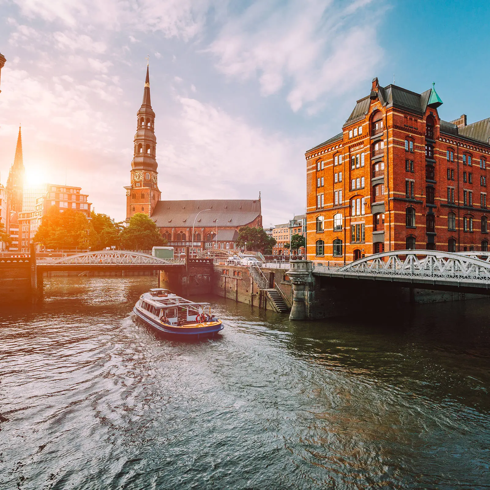 Speicherstadt mit Backsteinhäusern an der Elbe. Auf dem Fluss fährt eine Fähre.