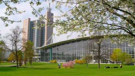 Gläserne Messe Hannover vor der eine große Wiese ist.