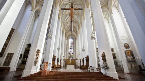 Altar innerhalb der Frauenkirche. Darüber hängt ein großes Kreuz mit Jesus.