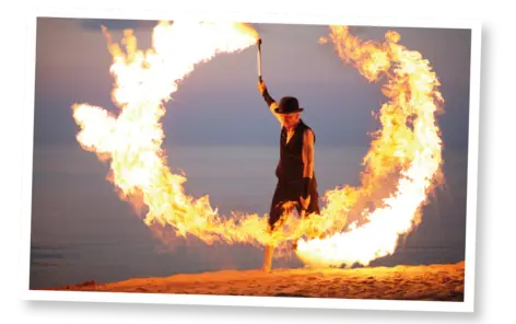 Ein schwarz gekleideter Mann schwingt eine Fackel, so dass das Feuer einen Kreis bildet.