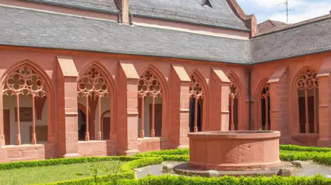 Innenhof der Pfarrkirche St. Stephan mit einem kleinen Garten und einem Brunnen.