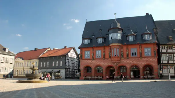 Marktplatz von Goslar mit alten Fachwerkhäusern. In der Mitte steht ein Brunnen.