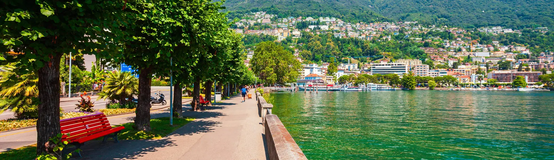 Blick entlang der Promenade von Locarno am Lago Maggiore. An der Straße stehen Palmen.