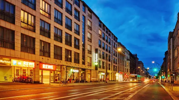 Beleuchtete Straße vor dem Hotel bei Nacht.