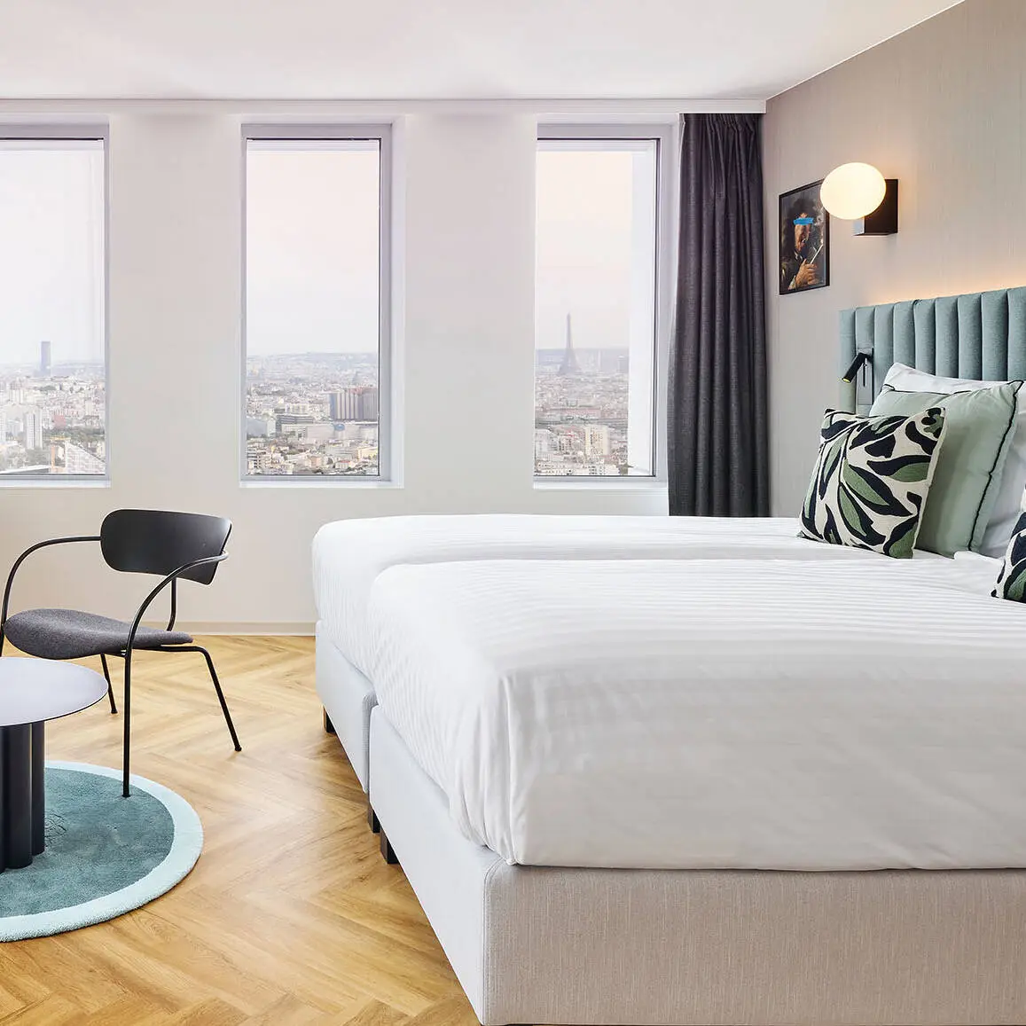 Hotel room with a large double bed. There is a large window seat by the window to look out over the city.